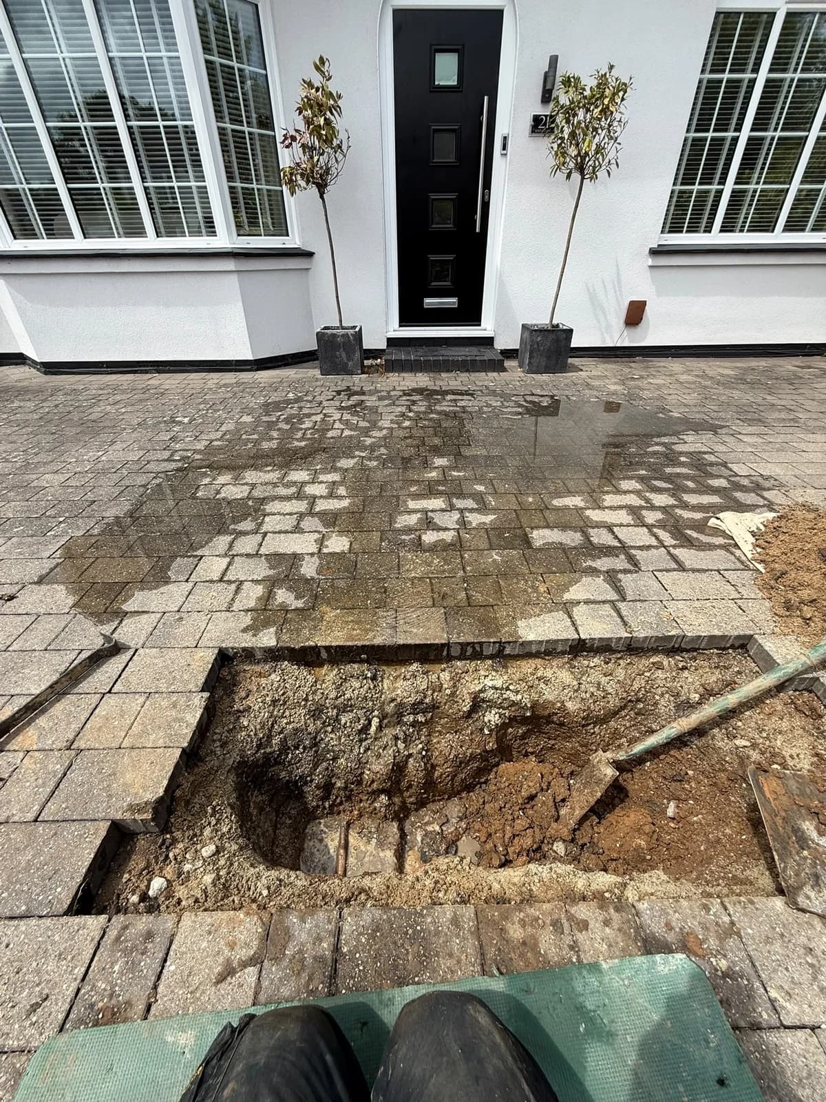 Small targeted excavation in a block-paved driveway exposing the located mains water leak in Bridgend